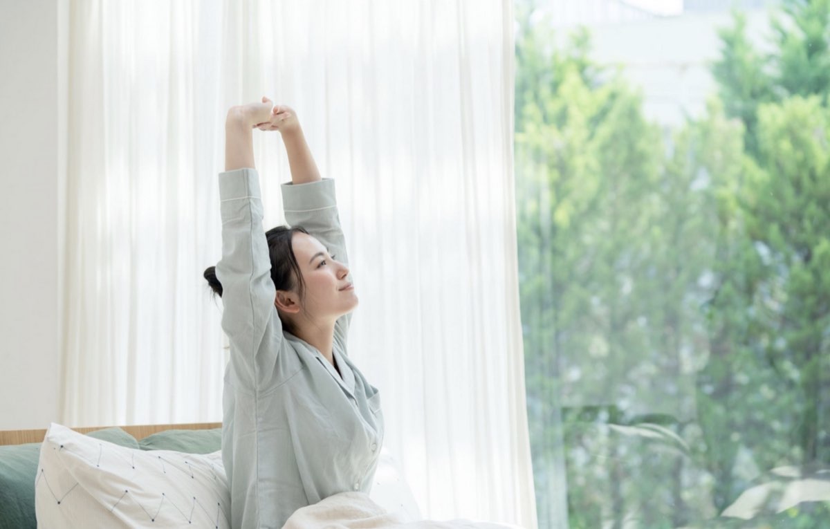 朝、すっと背筋を伸ばして光を浴びる女性